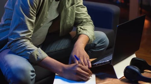 Young Adult Working on Laptop and Taking Notes
