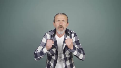 Aggressive Man Faces the Camera with Raised Hands
