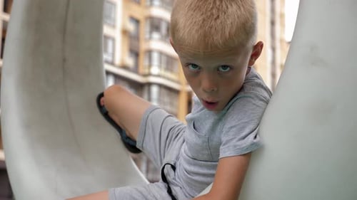 Blonde Haired Boy Sitting on Urban Playground