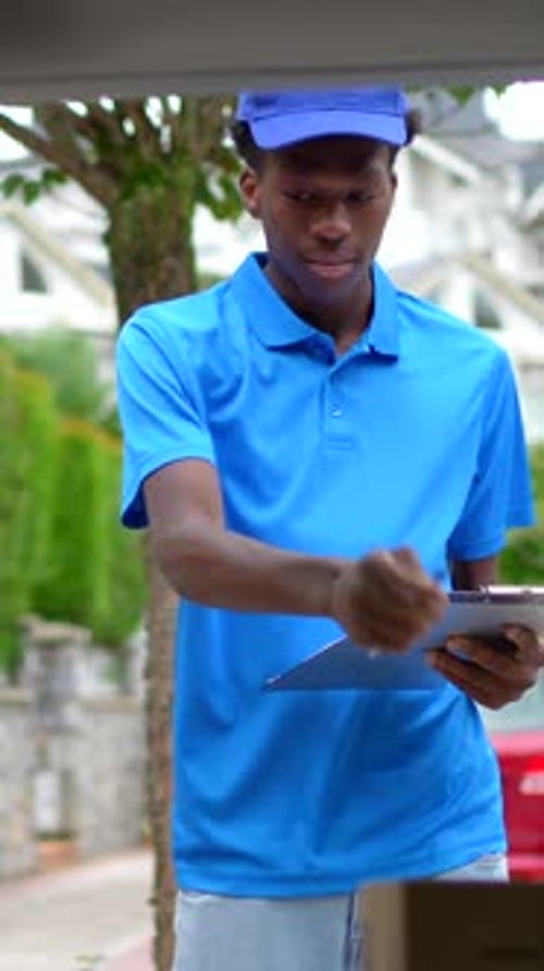 Young Adult Delivery Worker Writing on Clipboard Smiling