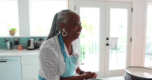 Smiling Woman in Kitchen Wearing Blue Striped Apron