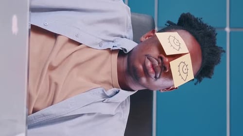 Creative Guy with Funny Sticky Notes on His Eyes During a Break in the Office