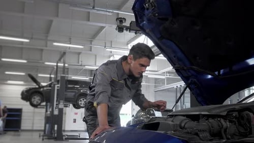 Engagierter Autoservicetechniker prüft akribisch das Öl in einem Fahrzeug mit offener Motorhaube