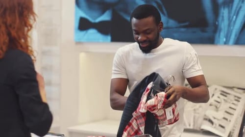 The Seller African American Man and the Customer in a Clothing Store Shopping Money Technology Buy