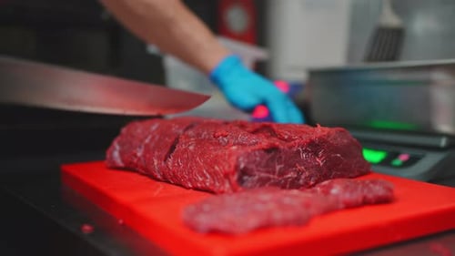 Butcher Cutting Fresh Meat on a Red Board