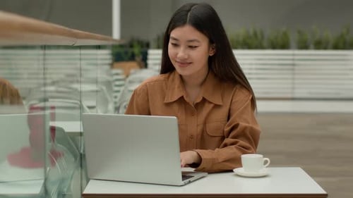 Smiling Woman Working on Laptop with Coffee