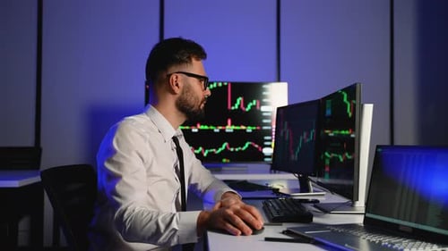Stock Trader Analyzing Financial Charts on Multiple Screens