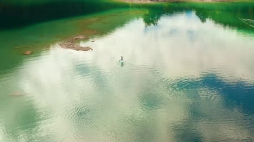 Man Swimming on the Sub Board or a Paddleboard in the Middle of the Lake
