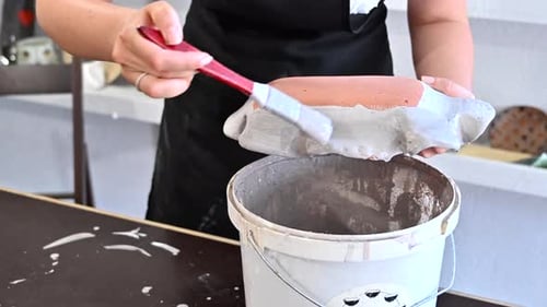 Woman painting a flower vase at pottery workshop