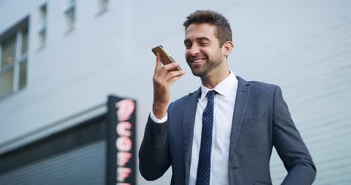 4k video footage of a handsome young businessman using his cellphone while out in the city