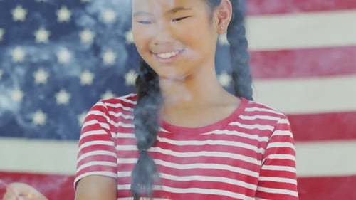 Smiling girl holds sparkler with American flag background