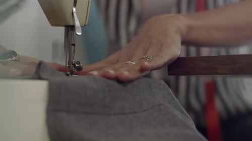 Close up of a Young female fashion designer working at home studio on sawing machine.