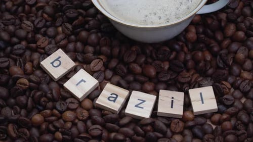 Coffee Beans with the Inscription Brazil and a Porcelain Cup with Coffee on Them