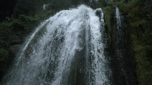 Curved waterfall cresting over mossy ridge with mist in Ultra slow motion captured with a