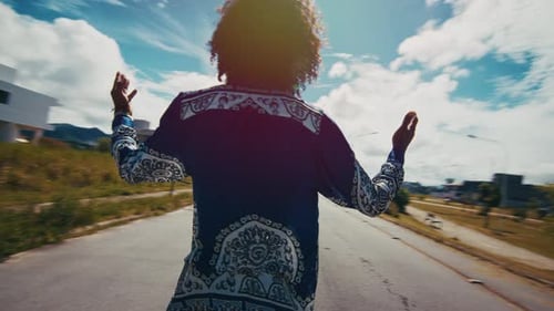 Homem africano em roupas autênticas fica com as mãos estendidas na rua e no fundo urbano