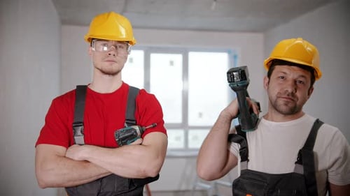 Two Men Workers Standing in Draft Apartment Holding Instruments