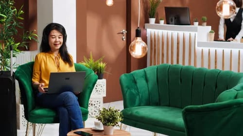Asian Tourist Ordering Coffee Cup While She Works on Laptop