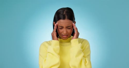 Headache, woman and pain in studio for stress, vertigo and mental health on blue background