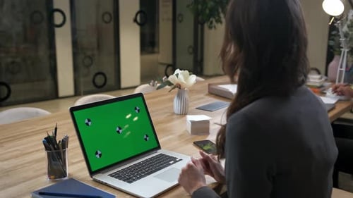 Woman manager in a blazer in a modern office talking at her laptop. Green screen
