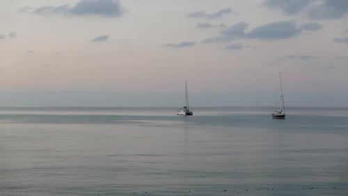 Two small yachts moored offshore at dusk. Cefalu. Sicily. Italy