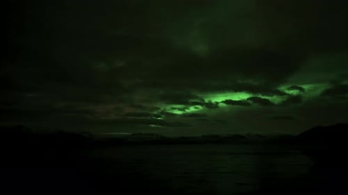 Time lapse shot of moving clouds at night sky lighting by northern lights.Spectacular shot of green