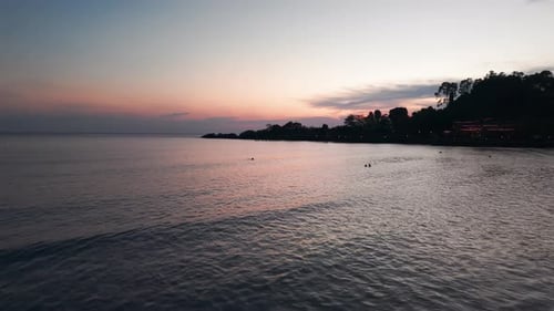 Tropical Beach at Dusk with Tourists Enjoying the Sunset