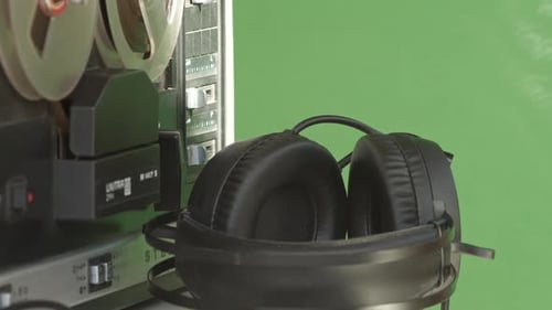Headphones and tape recorder playing magnetic deck, green screen background