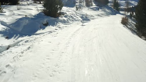 Skiing Down Snowy Mountain Trail on Sunny Day