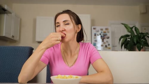 Woman Eats Potato Chips at Table Indoors
