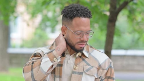 Young Man Experiencing Neck Pain Outdoors