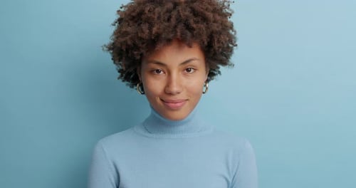 Smiling Woman Wearing Turtleneck on Blue Background