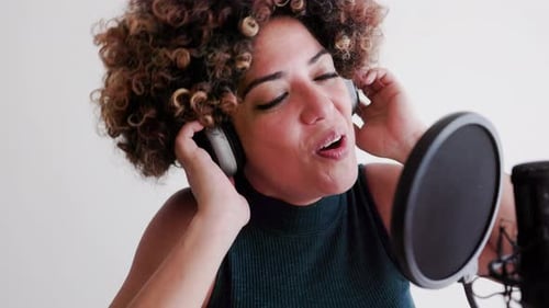 Female latin american singer recording music song on microphone at studio, Audio sound performance