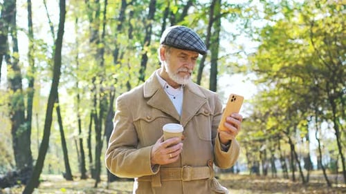 Senior Man Using Phone With Coffee in Park