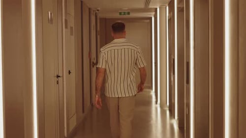Man Walking Down Modern Hotel Hallway