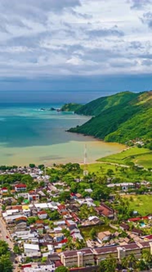Aerial hyperlapse over coastal town and bay in Bali, Indonesia on cloudy day, vertical