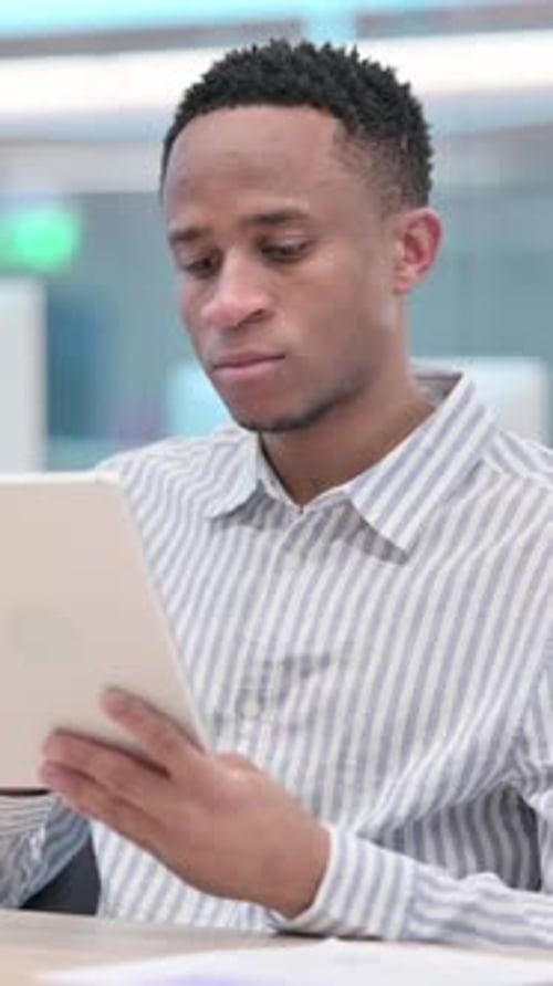 Attractive African Businessman using Tablet in Office, vertical video