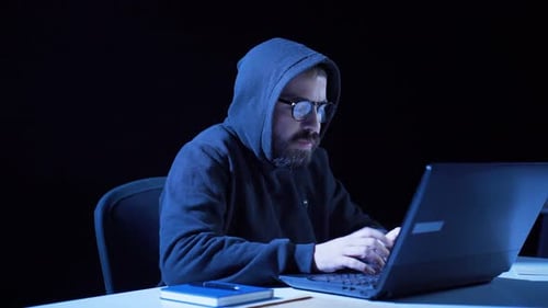 Young Adult Typing on Laptop in Dark Room