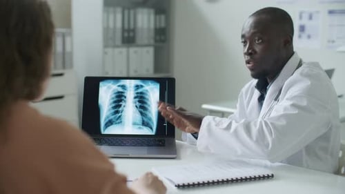 Black Doctor Discussing Chest X-Ray Image with Patient in Medical Office