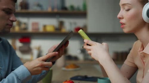 Millennial Couple Using Modern Gadgets Separately Enjoying Music in Headphones Closeup. Young