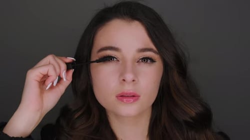 Elegant Woman Applying Mascara in Close Up