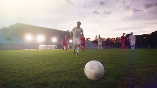 Soccer Players Train on Field at Dusk