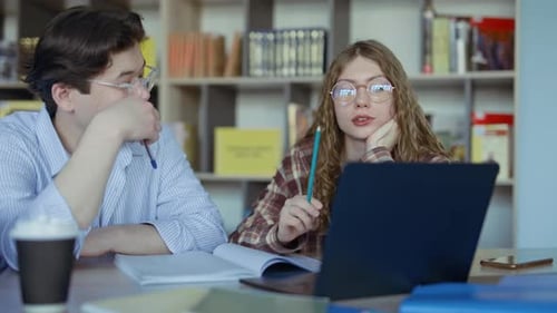 Dos estudiantes universitarios que estudian juntos en una biblioteca