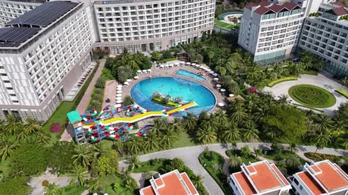Late afternoon aerial footage of a resort with large modern buildings around a central pool featurin