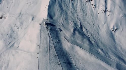 Vue aérienne extrême des pistes de ski sur une pente de montagne abrupte recouverte de neige