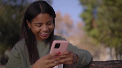 Smiling Woman Using Cellphone in a Park