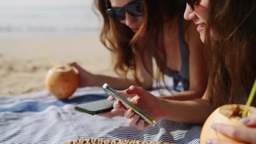 Cheerful Girls Tan Surf Internet on Phones at Sandy Beach Happy Ladies Sunbathing Texting on Devices