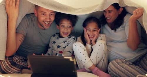 Happy Family Under Blanket Fort With Tablet