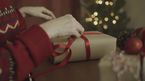 Woman Tying Red Ribbon On Christmas Gift
