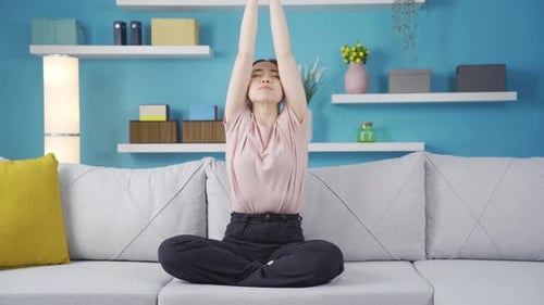 Woman Practices Yoga on Couch at Home