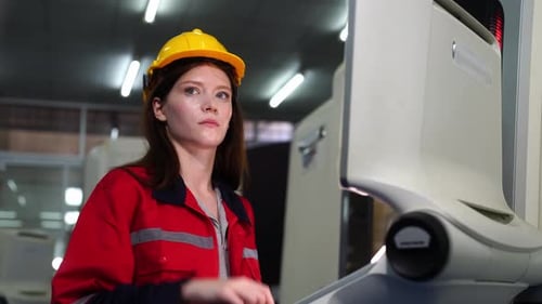 Young industrial worker operating cnc machine at metal machining industry
